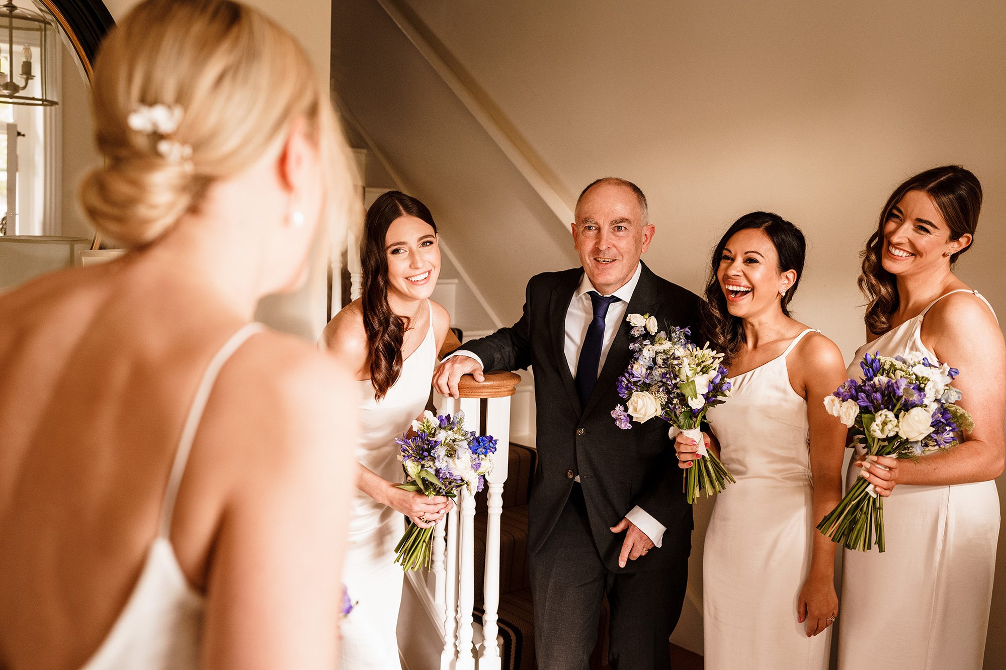 Proud father and bridesmaids see bride ready for the ceremony in her wedding dress for the first time at Primrose Hill Farm, Banbury, Oxfordshire.