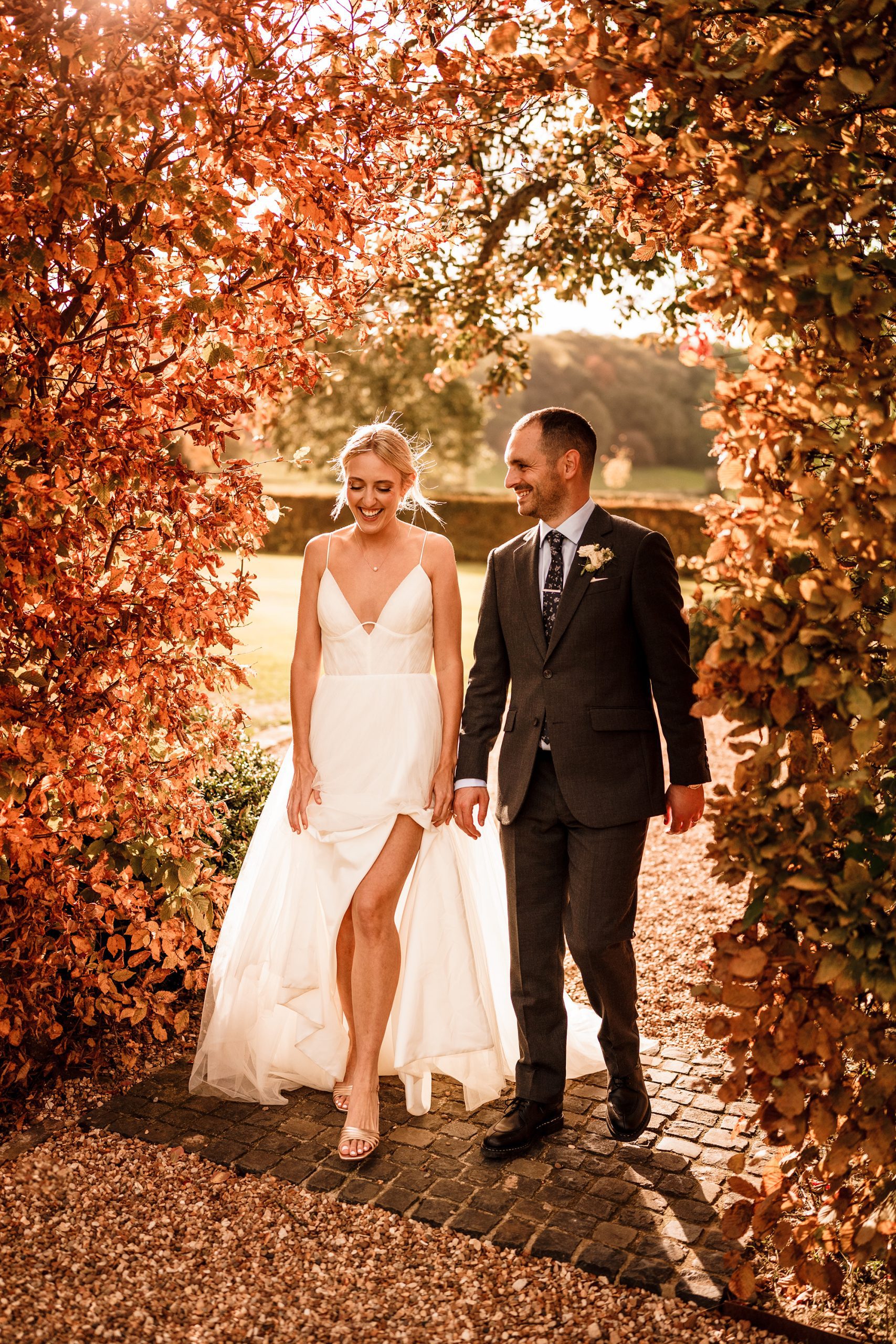 Bride and Groom walk through a golden arch of autumnal foliage at Primrose Hill Farm.