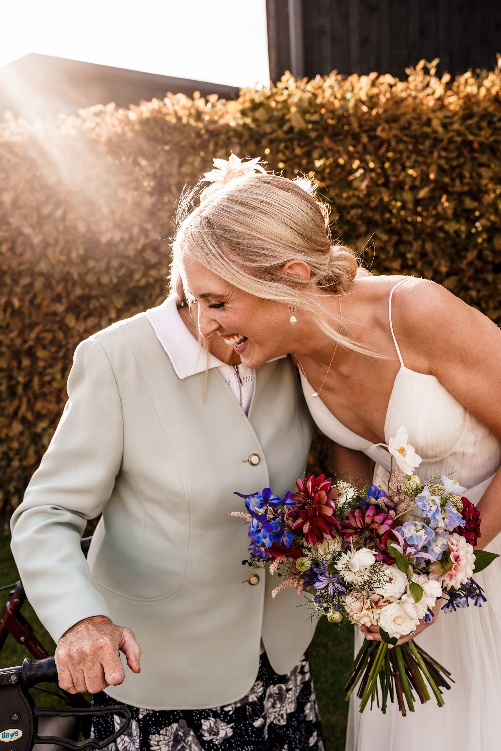 Bride laughing and joking with elderly relative in the Oxfordshire sunshine.