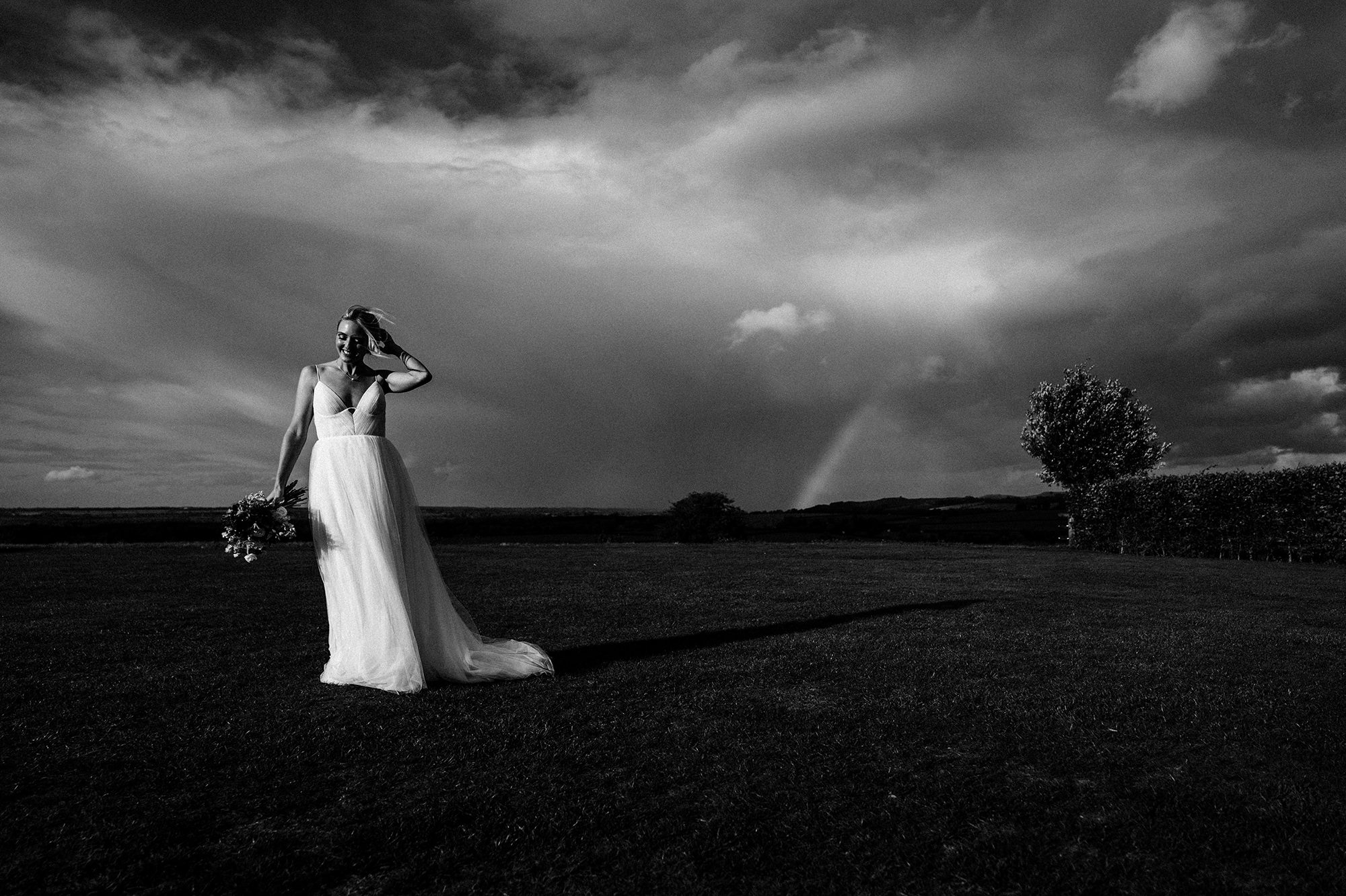 Bride poses in foreground with a stormy backdrop.