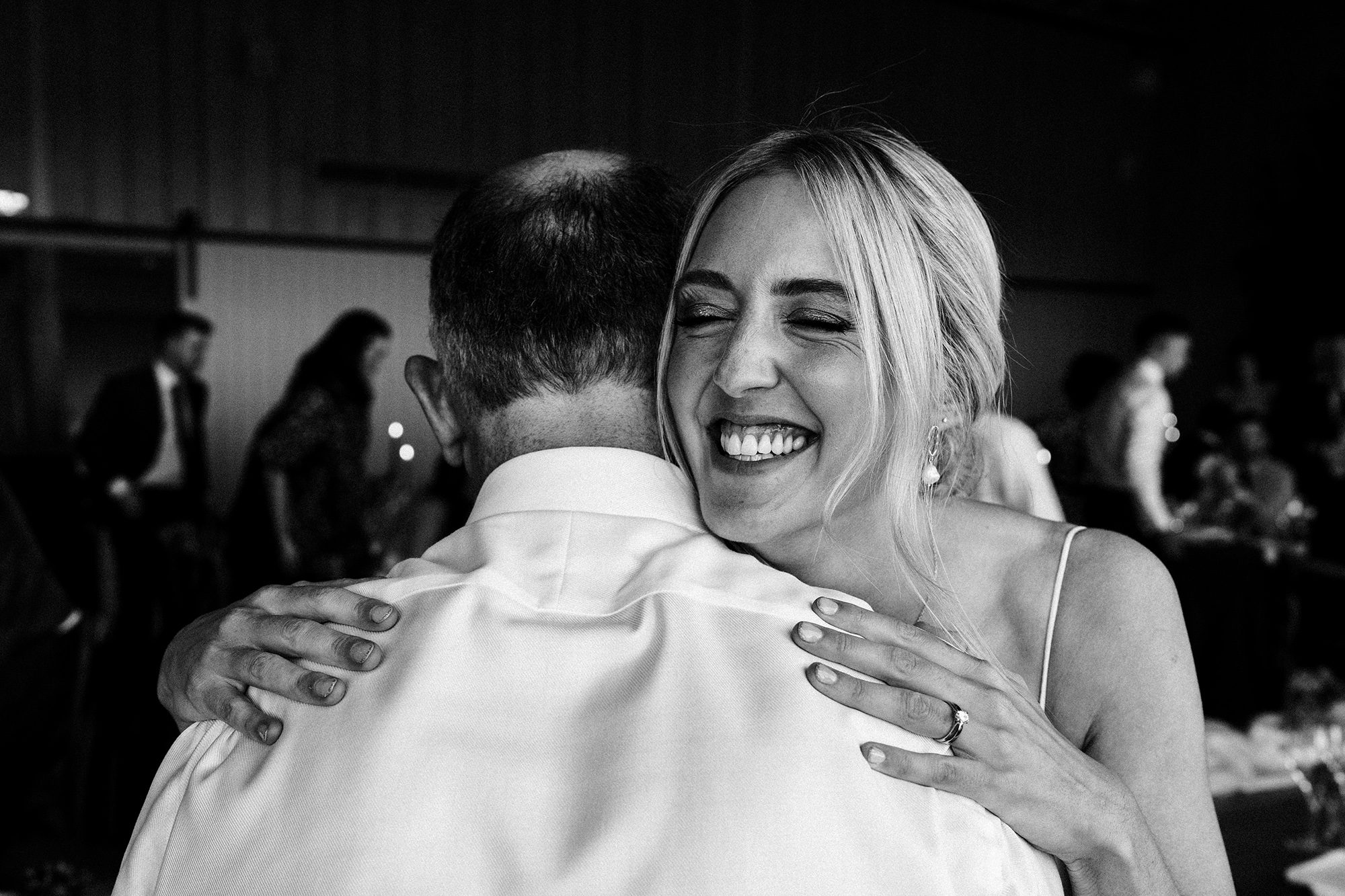 Grinning bride hugs a wedding guest with glee at Primrose Hall Farm.