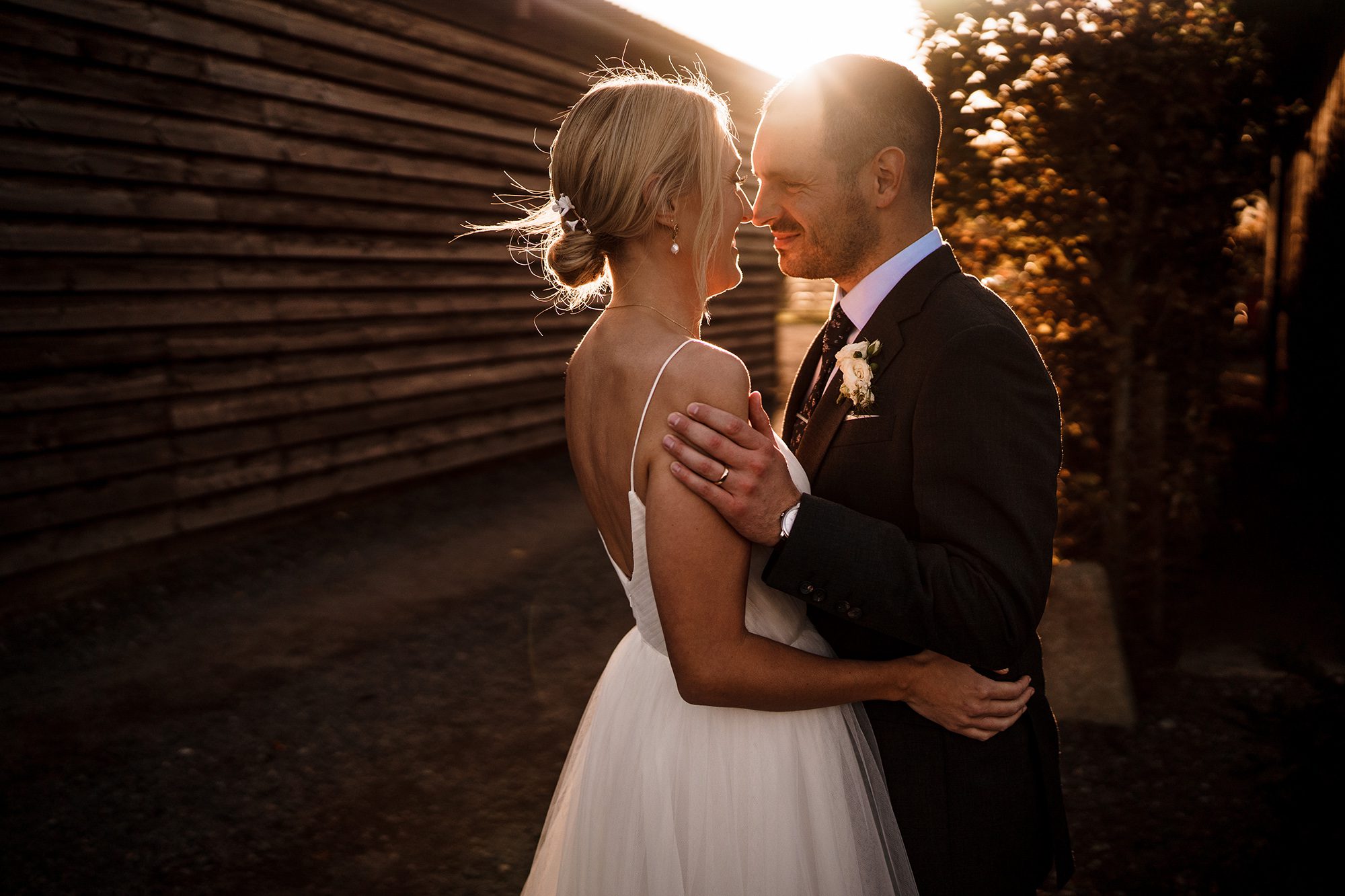 Sunlit embrace between bride and groom.