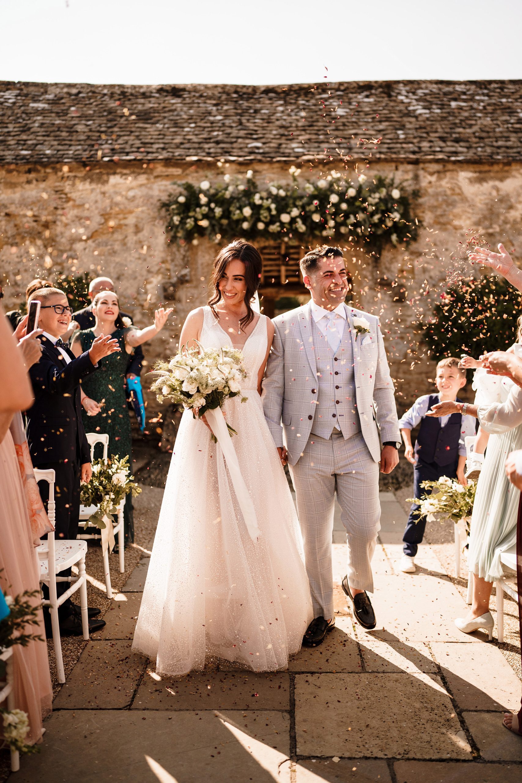 confetti is thrown over bride and groom with Caswell House in the background