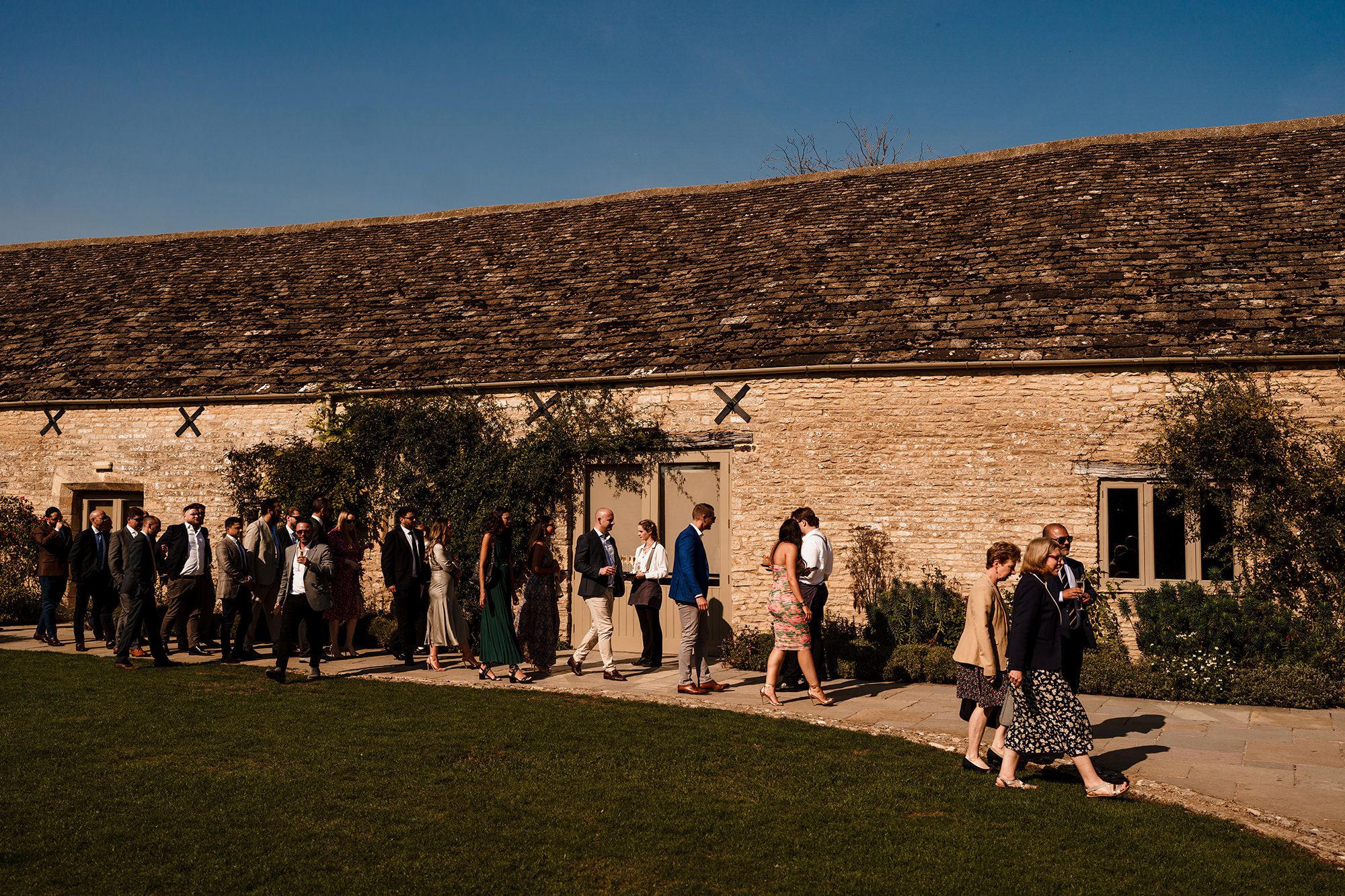 Caswell House wedding guests walk along stone wall