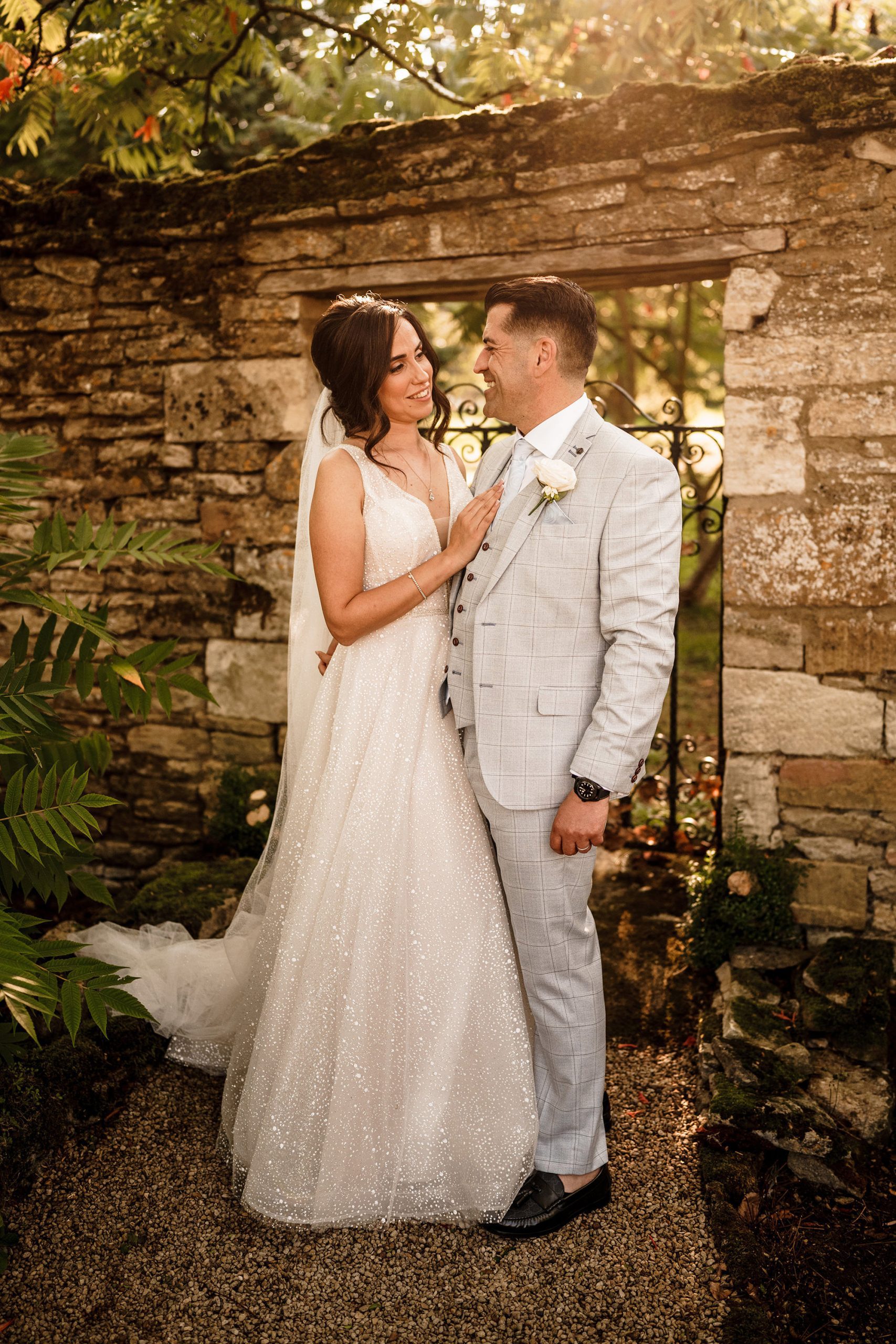 bride and groom in front of cotswolds stone and sunlight