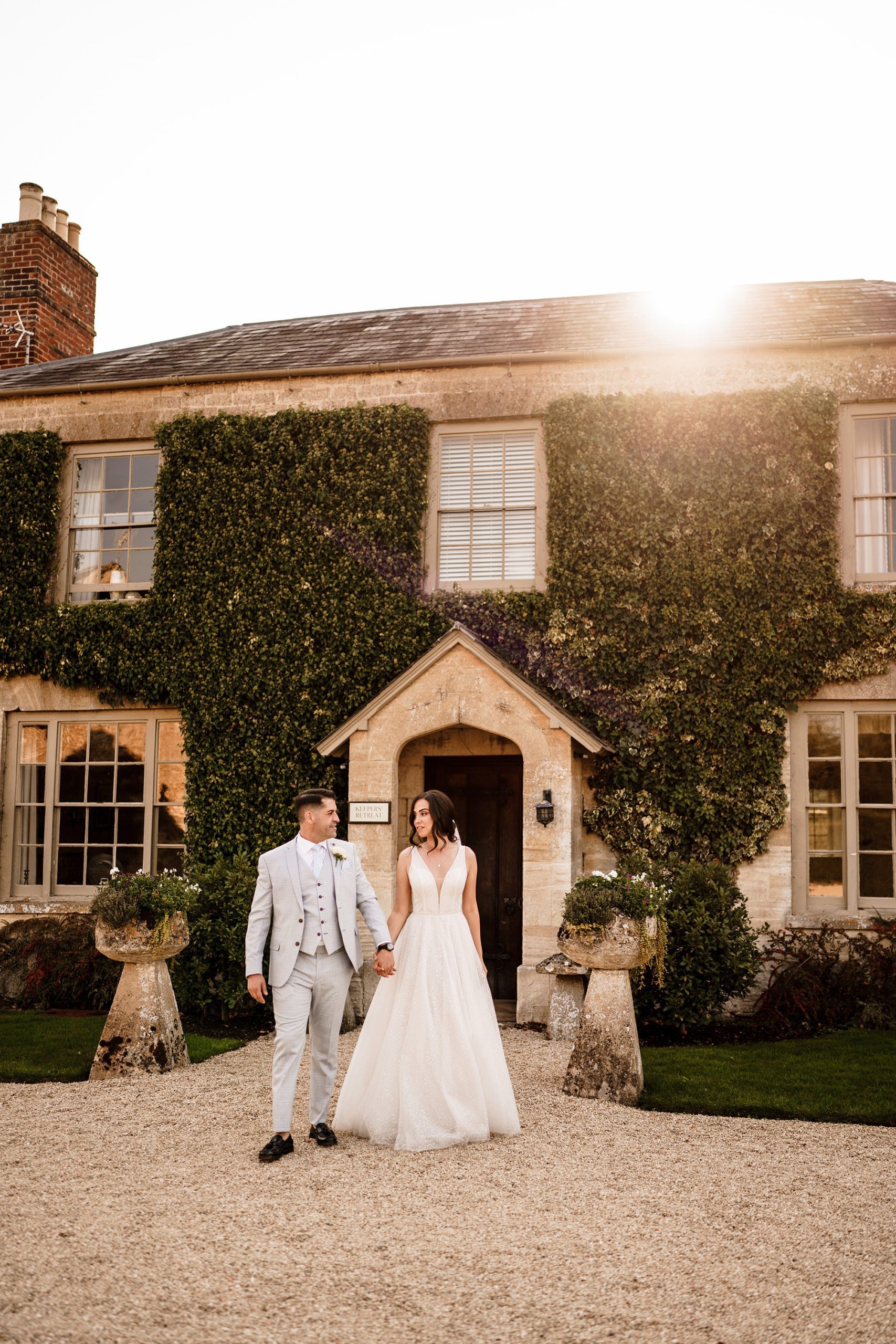 couple walking in backlit sunshine at Caswell House garden