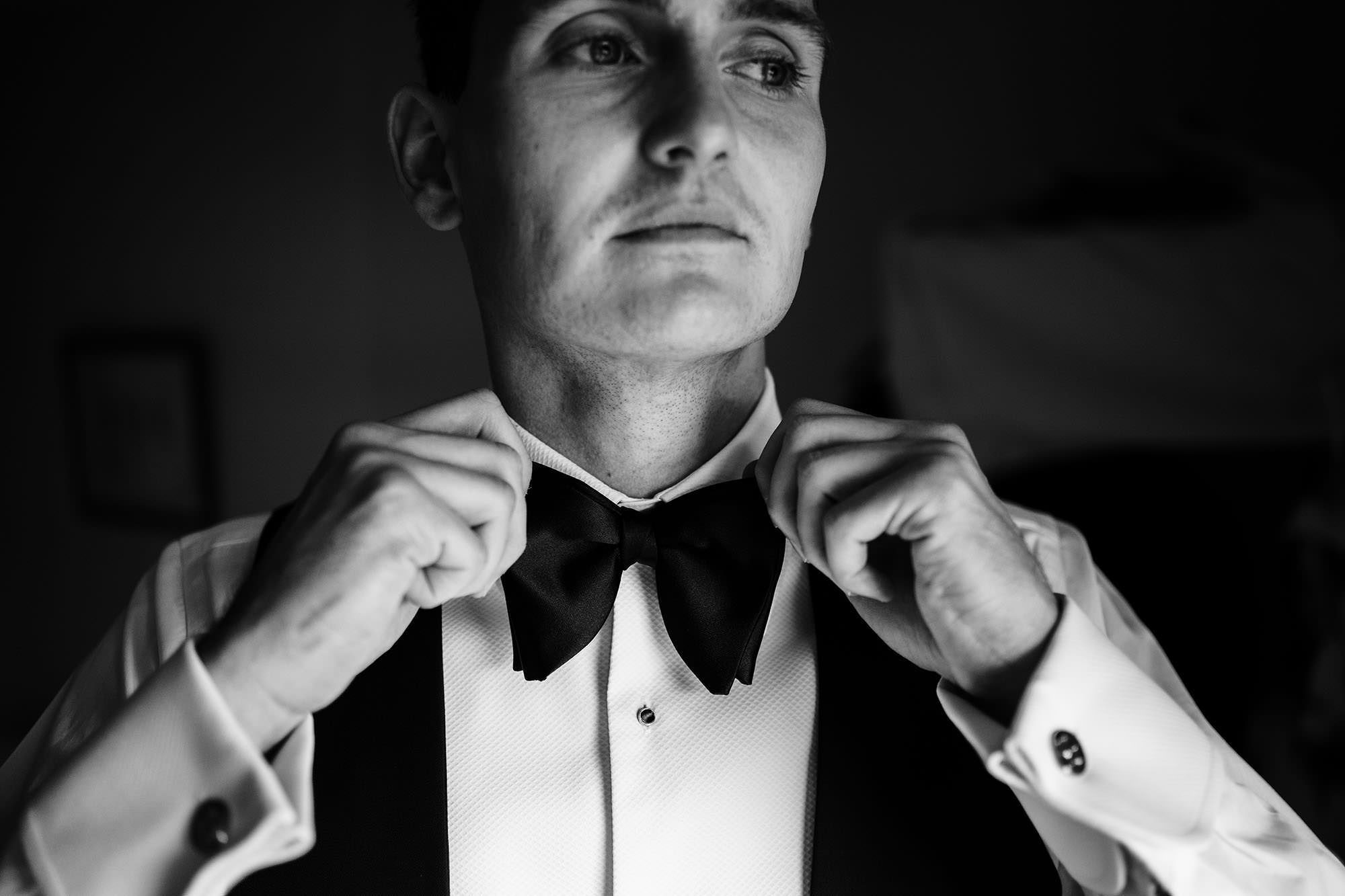 groom puts on his black tie for his London city wedding