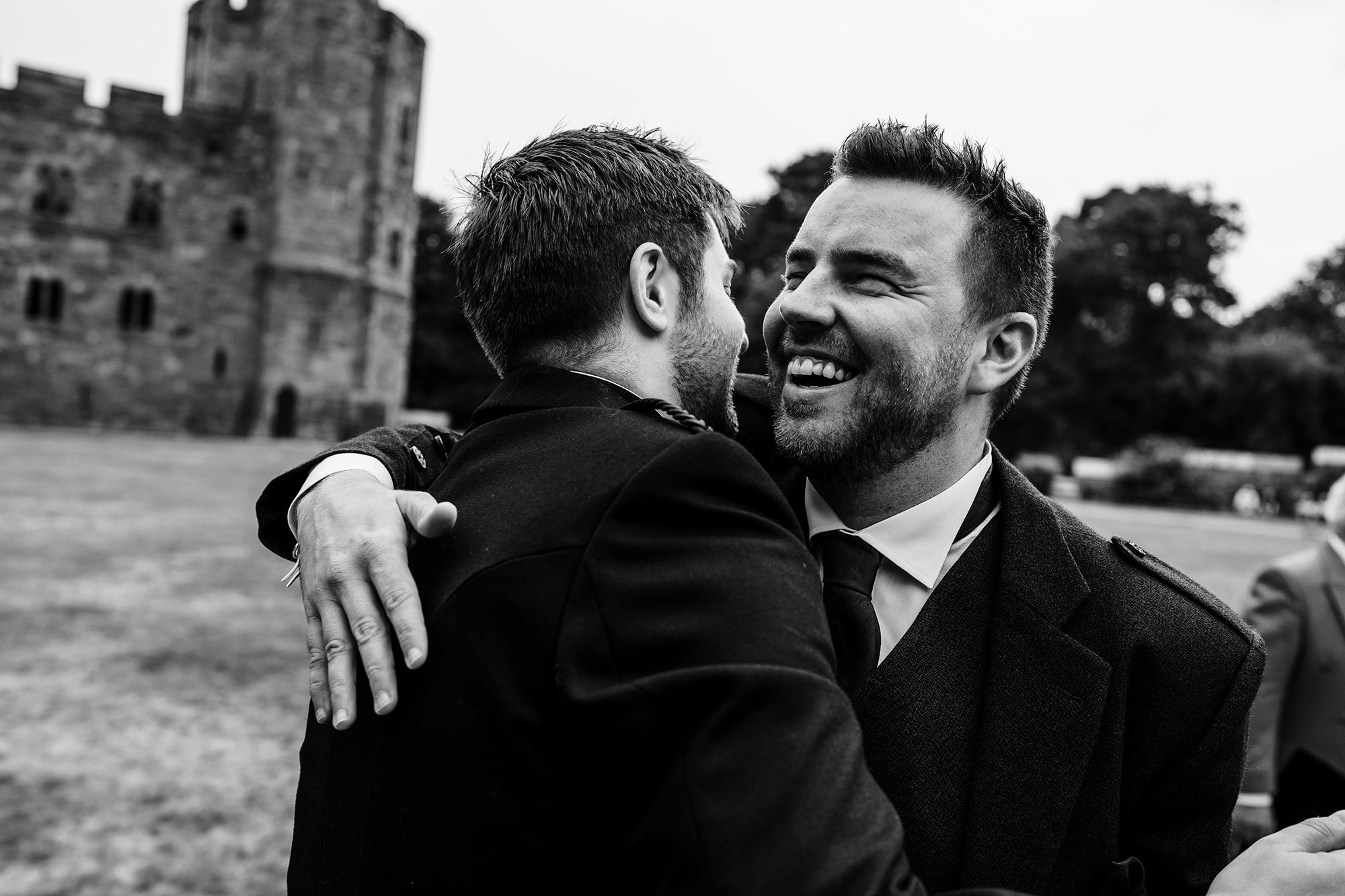 groom greets a friend on the grounds of Peckforton castle