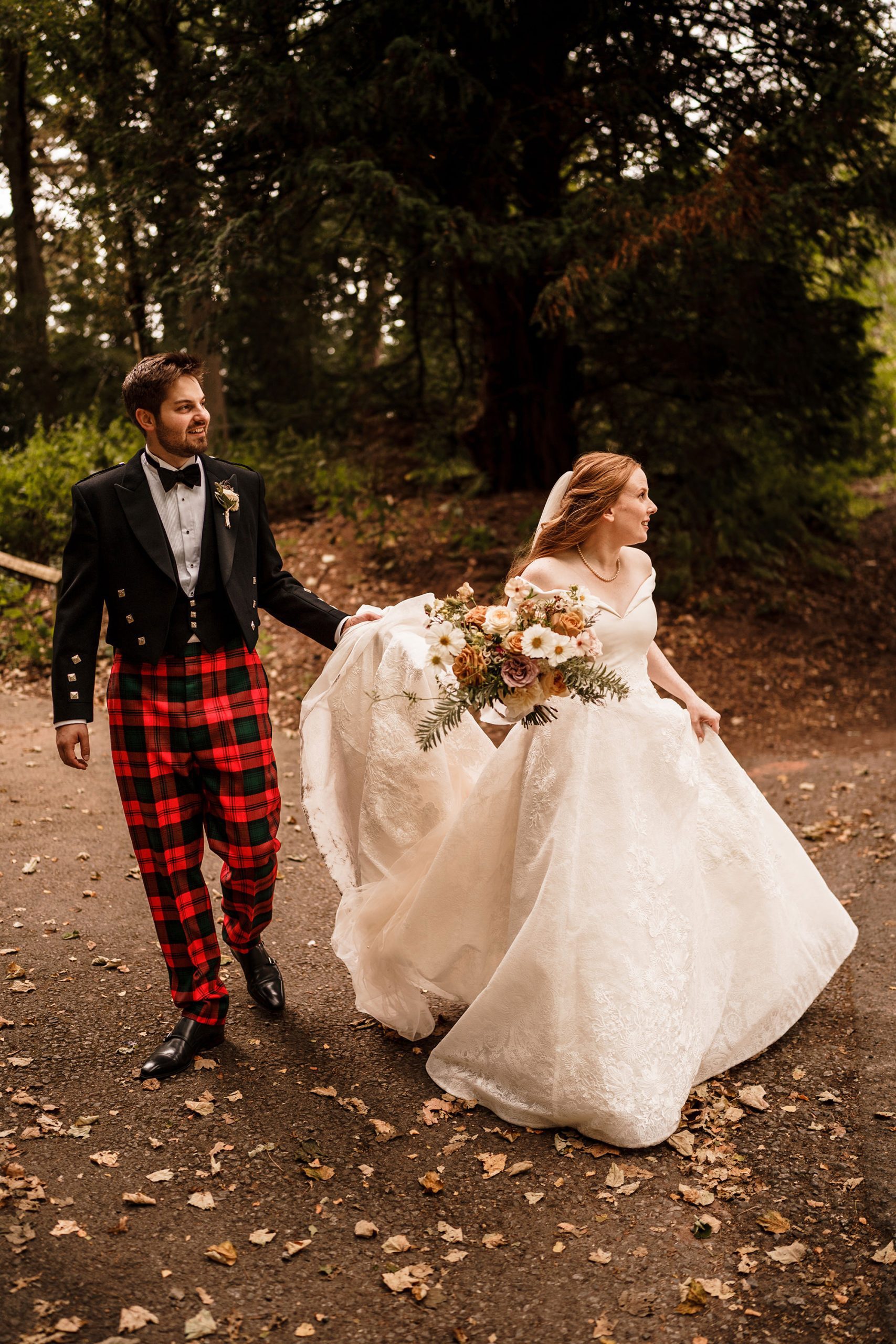 groom holds his brides dress during photo session at Peckforton Castle