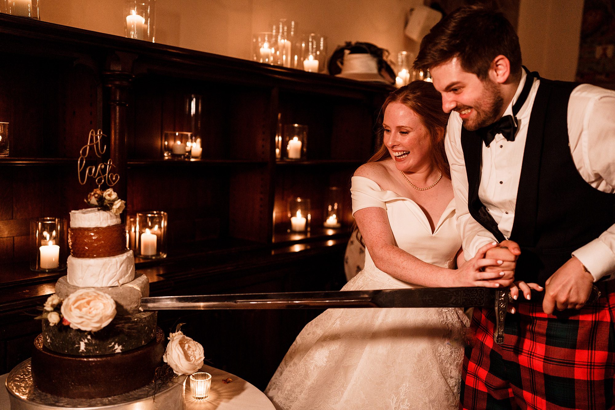 groom and his bride cut the wedding cake with a sword at Peckforton Castle