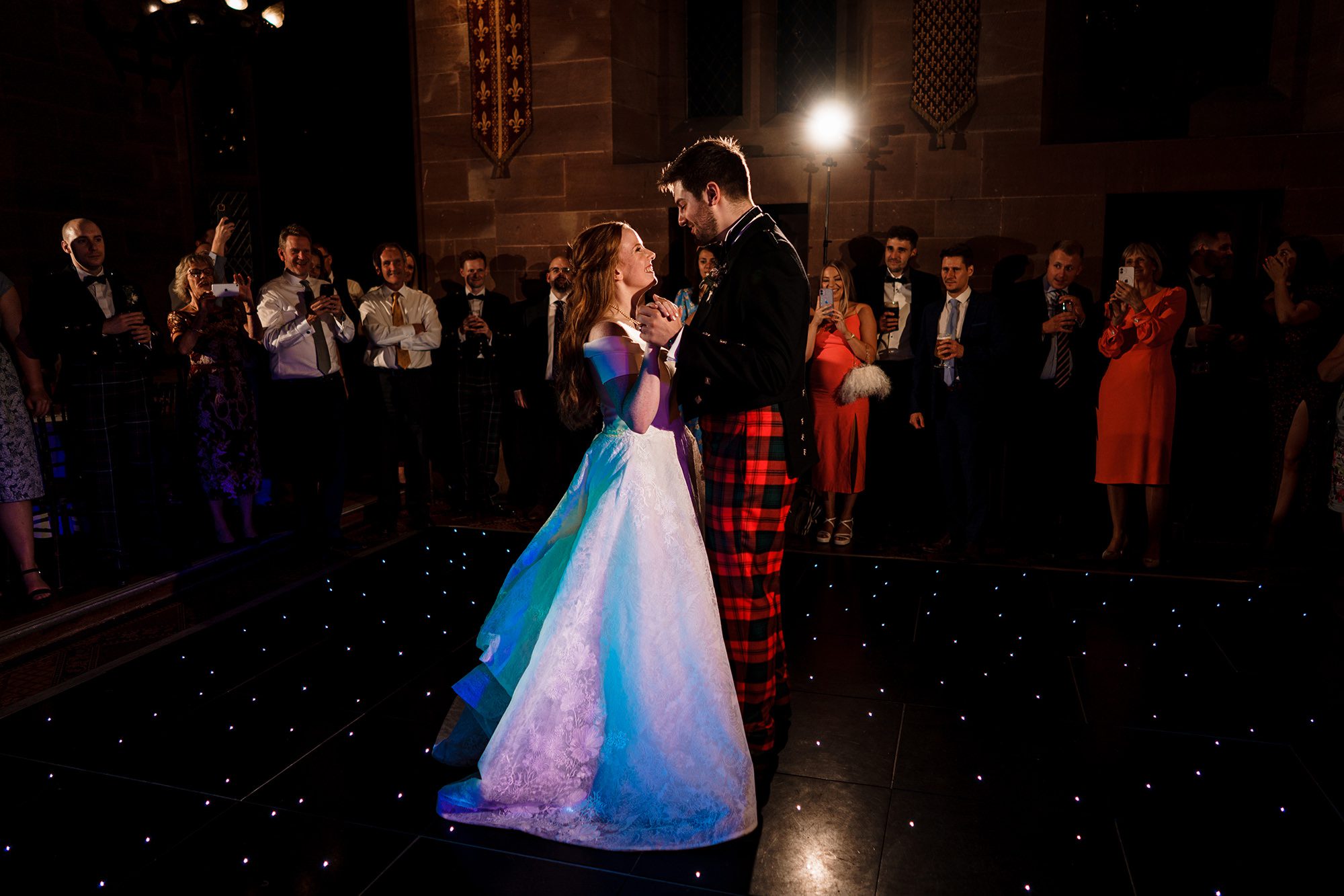 bride and groom having their first dance surrounded by wedding guests