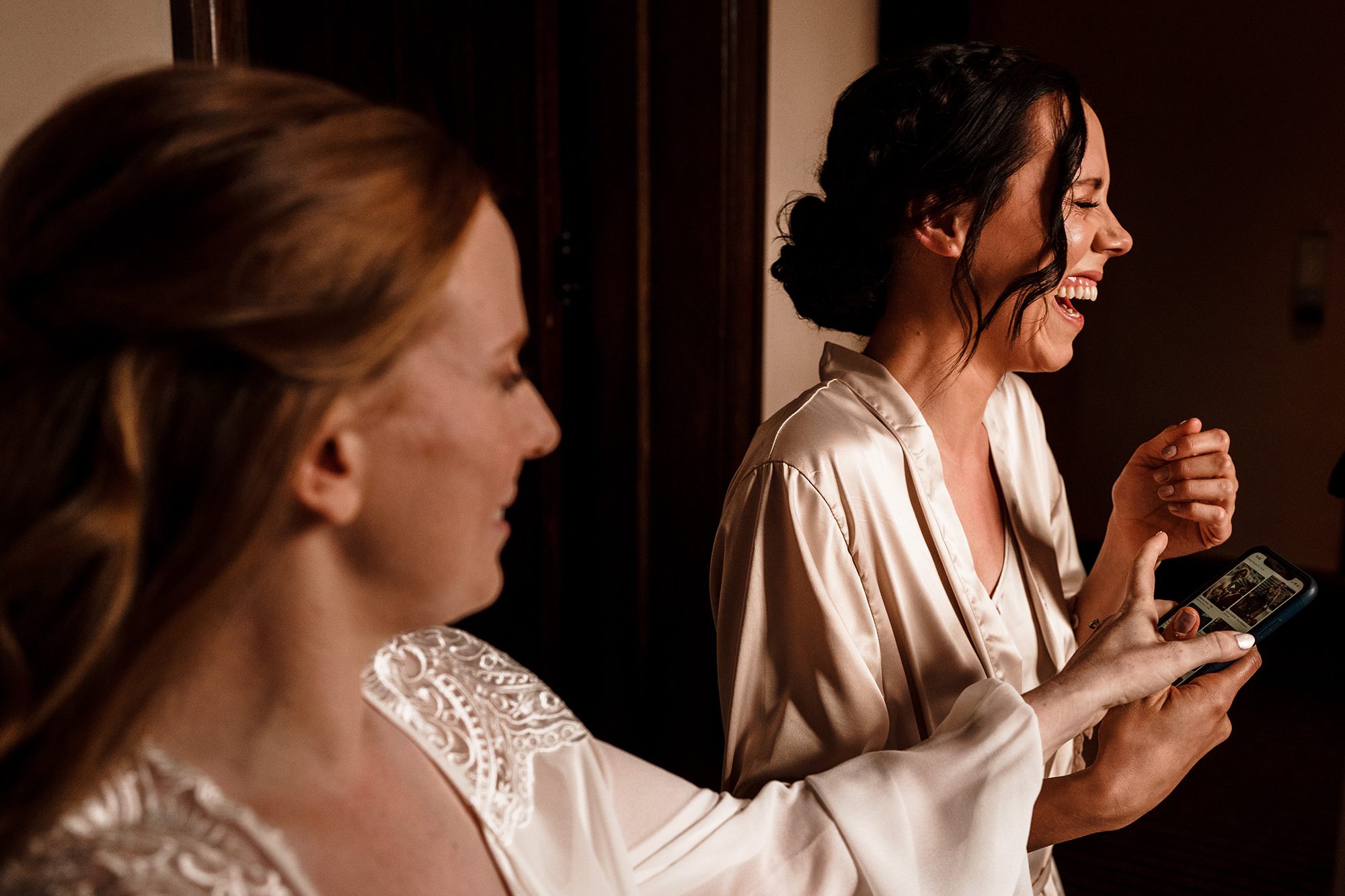 bride and her bridesmaid laughing during bridal preparations