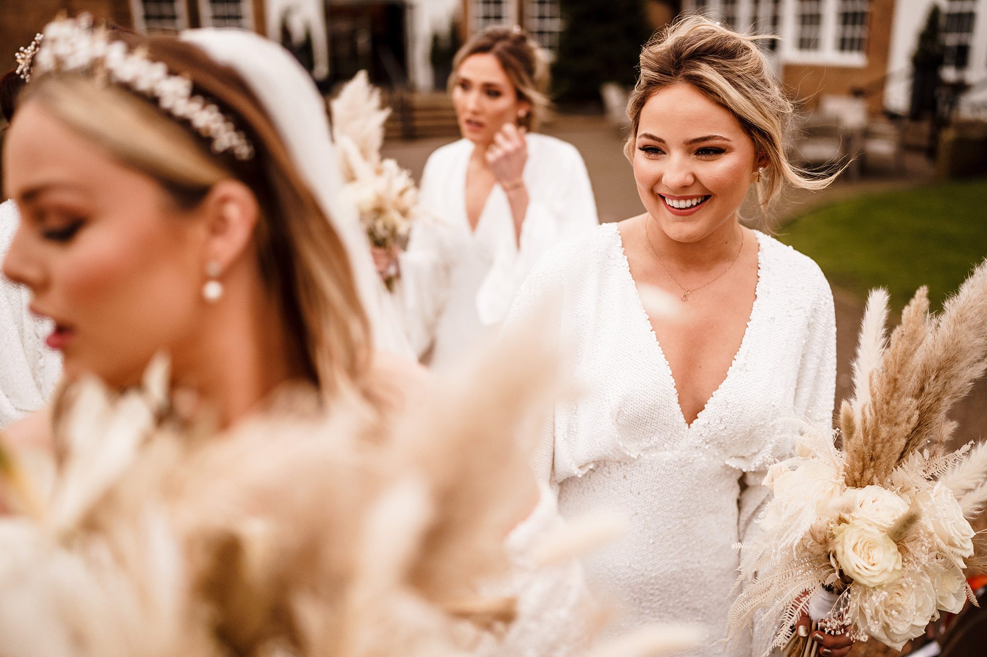 bridesmaid holding the brides dress walking towards wedding car