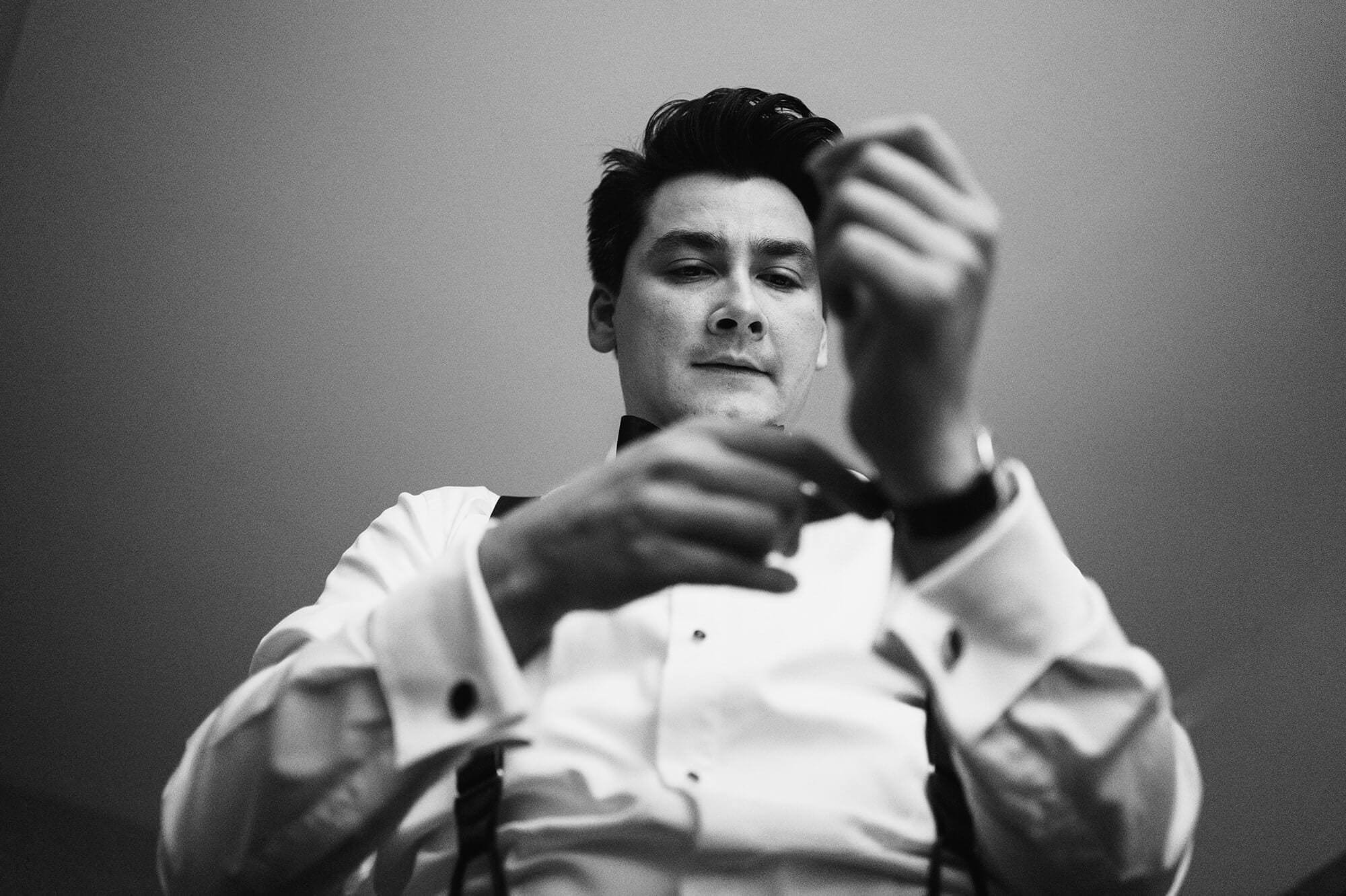 groom fastening his shirt before his wedding